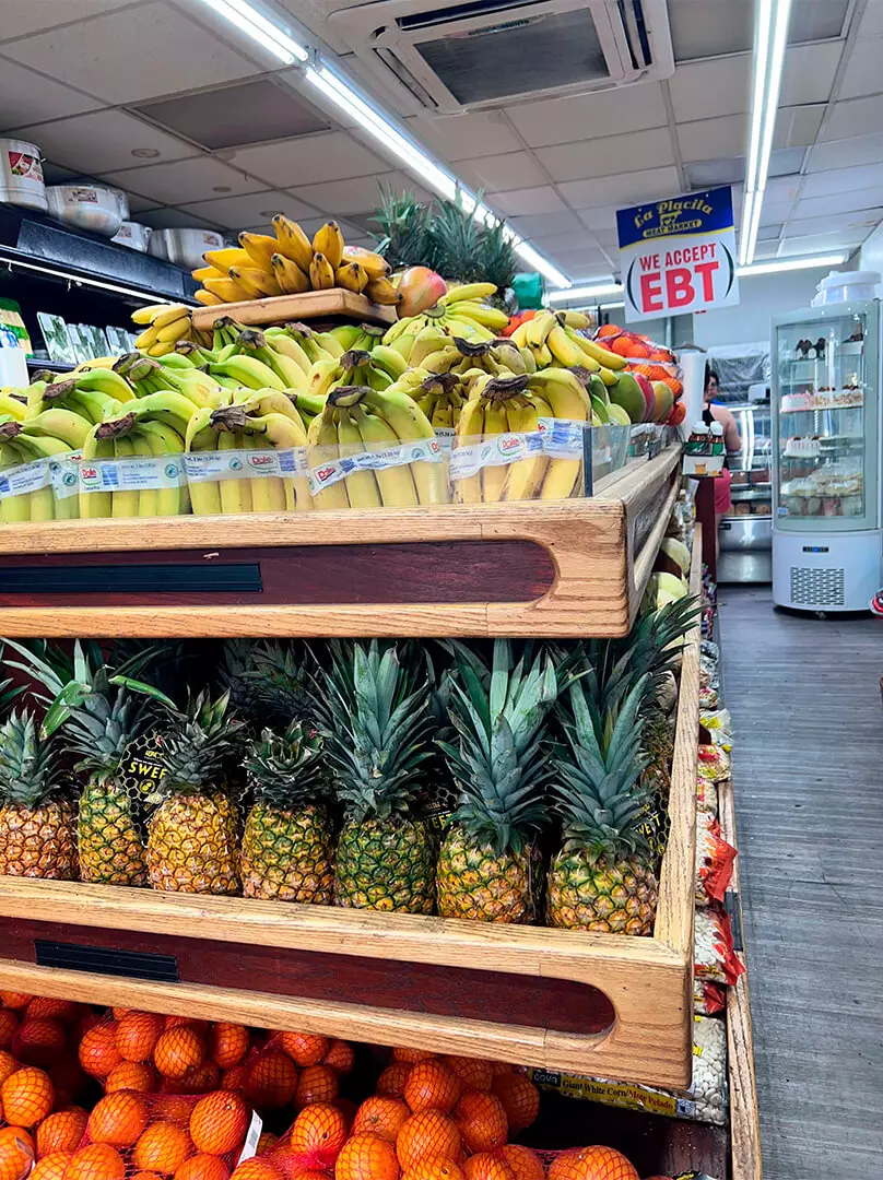 shelf with delicious and fresh fruits like pineapple, banana and orange at La Placita Meat Market