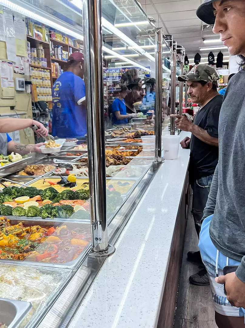 Image of a vegetable stand and a man attending the counter at La Placita Meat Market